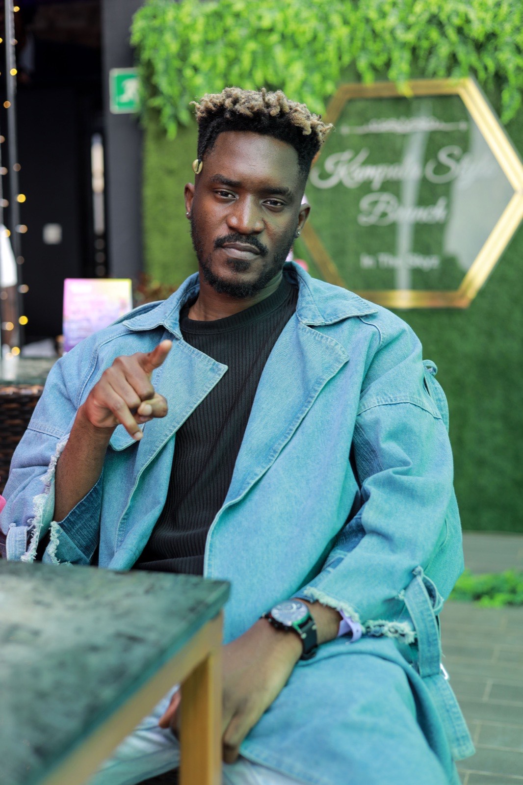 A guest poses beside The Kampala Style Brunch, In The Skyz backdrop, April 2024
