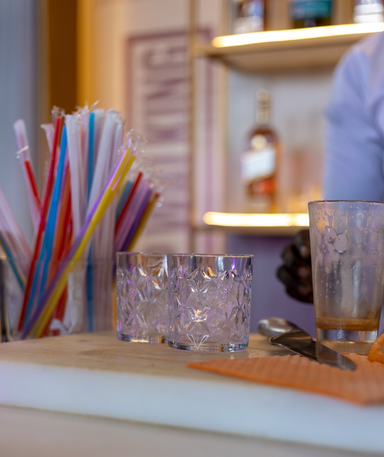 Cocktail glasses, colourful straws and a bartender at the bar counter at The Kampala Style Brunch, December 2024