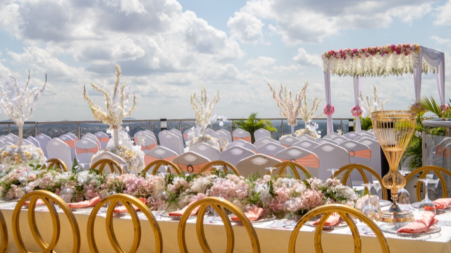 A wedding reception on Skyz Deck with a floral canopy, gold chairs and panoramic city views