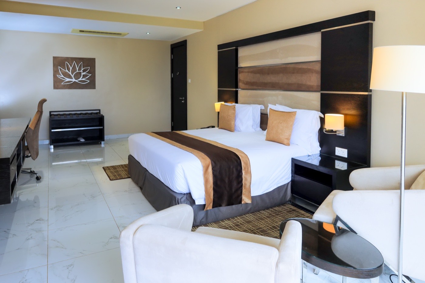 Guest bedroom with padded headboard and reading lamps at Skyz Hotel Kampala