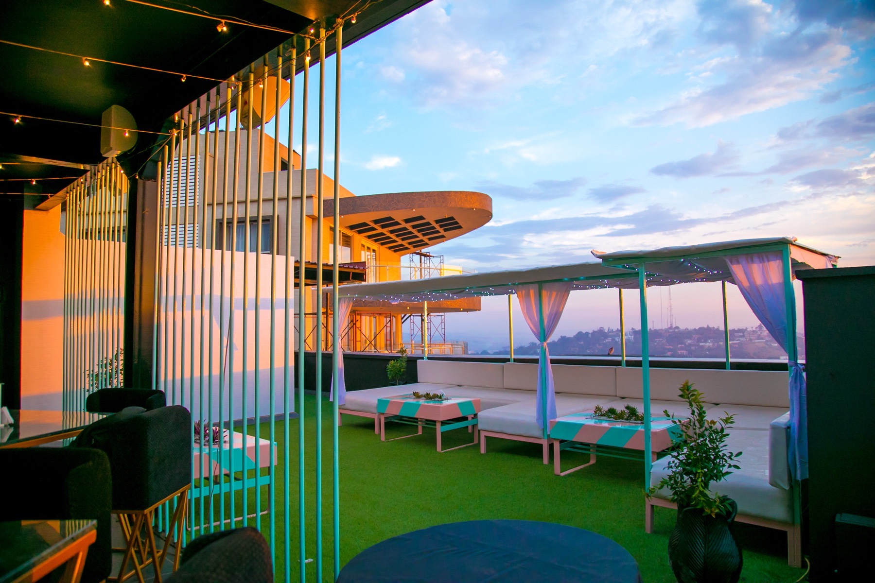 Lariza Terrace open-air rooftop at sunset with guests overlooking Kampala