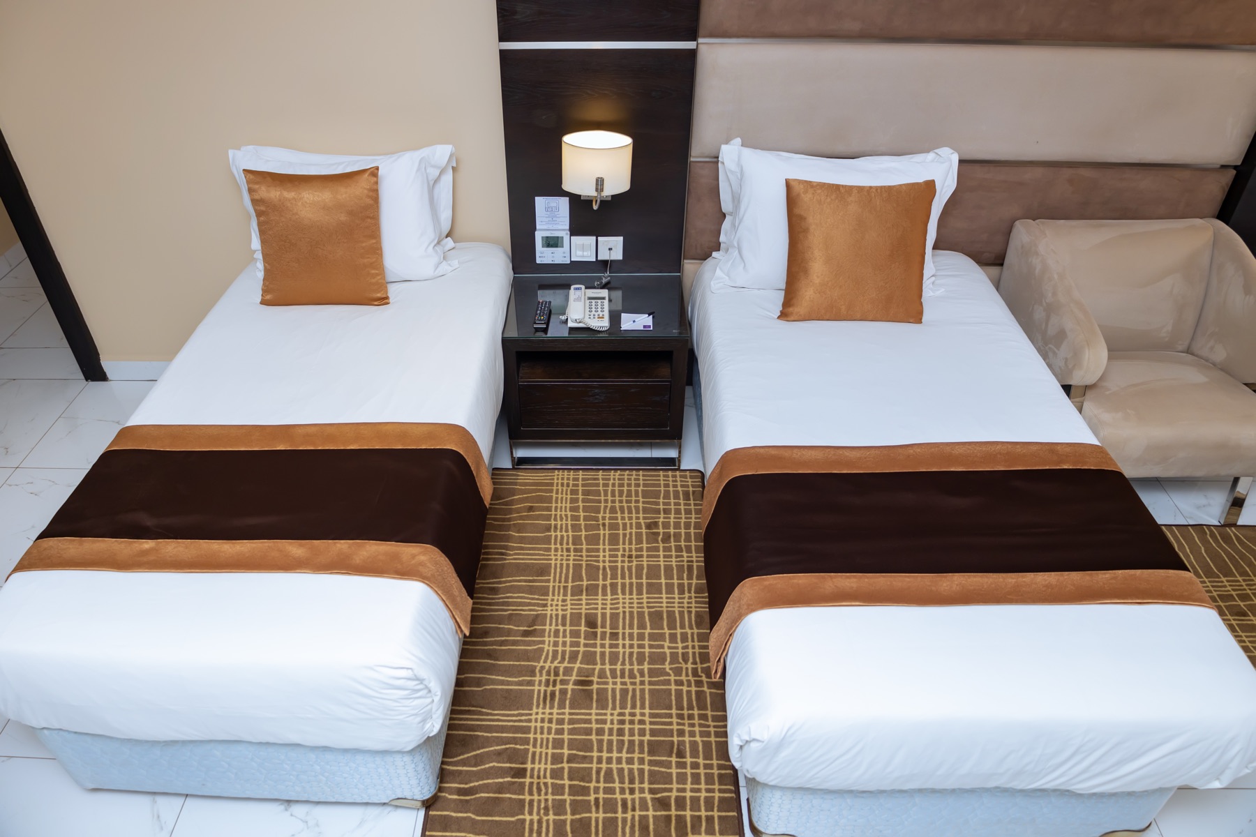 Twin beds with satin runners and gold cushions at the Twin Suite