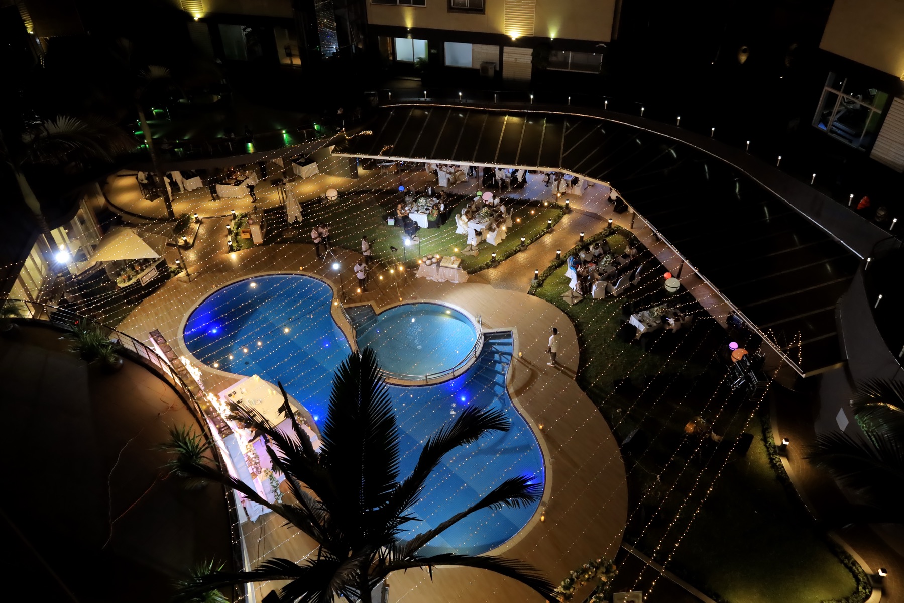 Aerial view of a wedding reception lit with string lights beside the Tropicanna Poolside at night